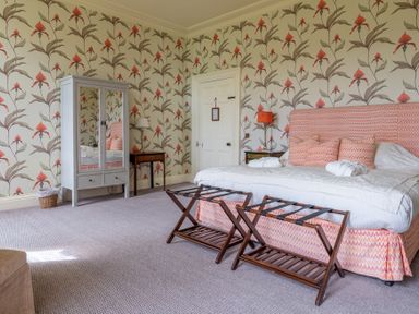 A bedroom with a bed two luggage racks a mirrored wardrobe two bedside tables and floral wallpaper at Silverholme Graythwaite near Hawkshead
