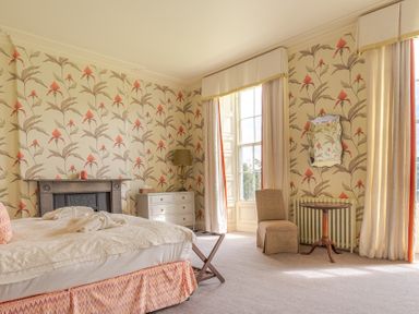 A bedroom with a bed a dresser a fireplace a chair and a small round table at Silverholme in Graythwaite near Hawkshead