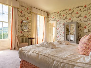 A bedroom with a large bed curtained windows a wardrobe and a chair at Silverholme in Graythwaite near Hawkshead