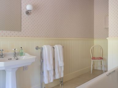 A bathroom with a pedestal sink towels on a rack a wooden chair and a bathtub at Silverholme Graythwaite near Hawkshead