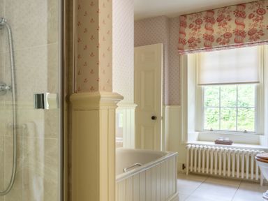 A bathroom with a bathtub shower radiator window with blinds and a door at Silverholme Graythwaite near Hawkshead