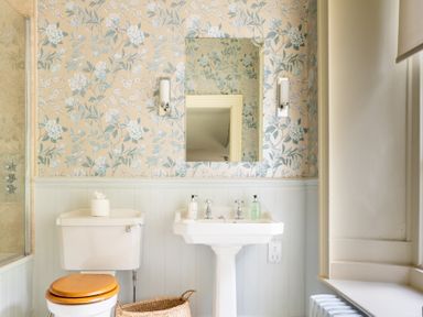 A bathroom with a toilet a pedestal sink a mirror and floral wallpaper at Silverholme Graythwaite near Hawkshead