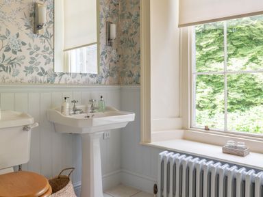 A bathroom with a pedestal sink and mirror next to a window with a radiator below at Silverholme Graythwaite near Hawkshead