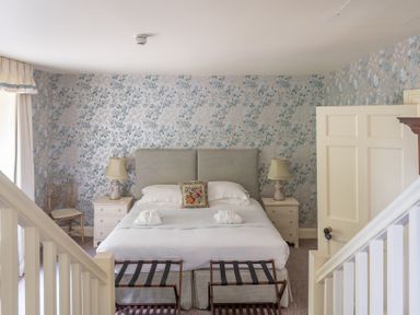 A bedroom with a double bed two bedside tables with lamps and floral wallpaper at Silverholme Graythwaite near Hawkshead