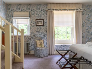 A bedroom with a window seat chair on carpeted floor near staircase at Silverholme in Graythwaite near Hawkshead