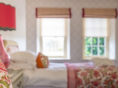 A bedroom with two beds pillows a bedside table and two windows at Silverholme in Graythwaite near Hawkshead