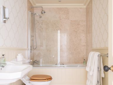 A bathroom with a bathtub shower combination a sink and a toilet with a wooden seat in Silverholme Graythwaite near Hawkshead