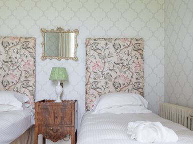 A bedroom with two single beds a wooden bedside table with a lamp and a mirror above at Silverholme Graythwaite near Hawkshead