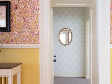 A hallway with patterned wallpaper and an oval mirror at Silverholme Graythwaite near Hawkshead