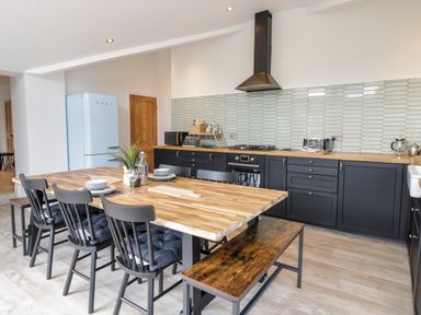 A kitchen with a wooden dining table chairs bench black cabinets and a light blue fridge at Coopers Rest Gorffwysfa Coopers in Dolwyddelan