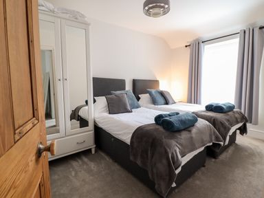A bedroom with two single beds grey headboards and a white wardrobe with mirrored doors at Coopers Rest Gorffwysfa Coopers in Dolwyddelan