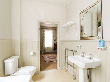 A bathroom with a toilet and sink and a mirror above the sink at Troon Cottage in Hunstanton
