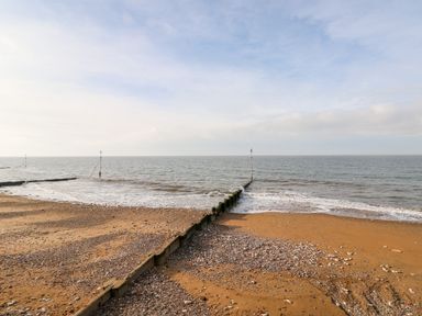 A sandy and pebbly beach with wooden groynes extending into the sea at Troon Cottage in Hunstanton