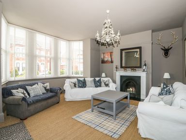 A living room with three sofas a gray coffee table and a fireplace at Troon Cottage in Hunstanton