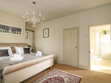 A bedroom with a bed towels chandelier and an ensuite bathroom at Troon Cottage in Hunstanton