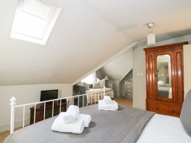 A bedroom with a bed and folded towels a wardrobe and a small TV at Troon Cottage Hunstanton