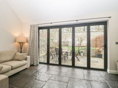 A living room with a beige sofa lamp and glass sliding doors leading to a patio at Willow Barn in Shapwick