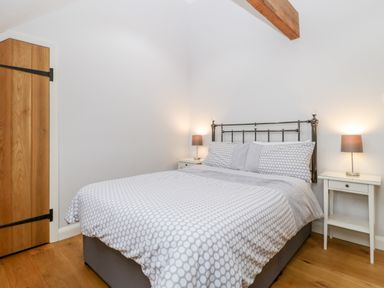 A bedroom with a bed with polka dot bedding two bedside tables with lamps and a wooden door at Willow Barn in Shapwick