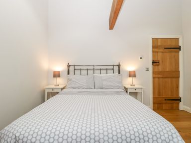 A bedroom with a double bed two bedside tables with lamps and a wooden door at Willow Barn in Shapwick