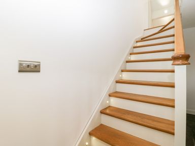 A wooden staircase with white walls and built-in step lights at Willow Barn in Shapwick