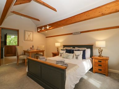 A bedroom with a large bed and wooden beams on the ceiling at The Coach House Apartment in Bredon