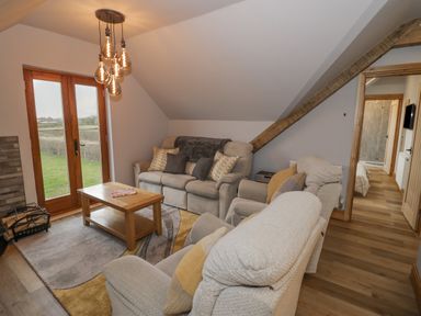 A living room with sofas a wooden coffee table and glass doors leading outside at Hallgarth Farm Holiday Lodge in Peopleton