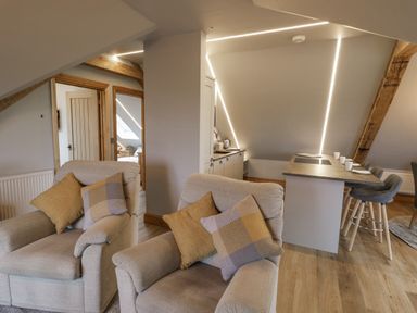 A living area with two armchairs and a kitchen island with bar stools at Hallgarth Farm Holiday Lodge in Peopleton