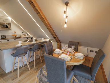 A dining area with a round table set for four and a kitchen island with three stools at Hallgarth Farm Holiday Lodge in Peopleton
