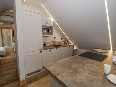 A kitchen with white cabinets a microwave coffee mugs and an induction cooktop at Hallgarth Farm Holiday Lodge in Peopleton