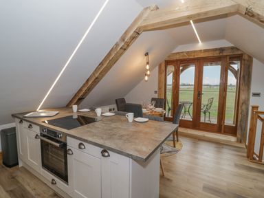 A kitchen with an island and a dining table near glass doors overlooking a field at Hallgarth Farm Holiday Lodge in Peopleton
