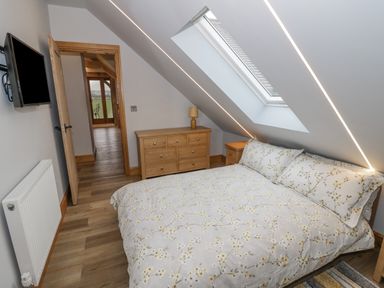 A bedroom with a bed under a skylight and wooden furniture at Hallgarth Farm Holiday Lodge in Peopleton