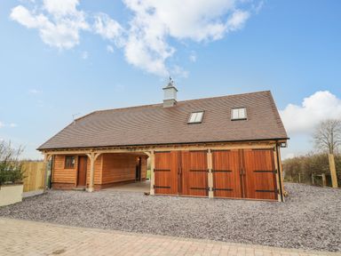 A detached wooden garage with three large doors and two skylights at Hallgarth Farm Holiday Lodge in Peopleton