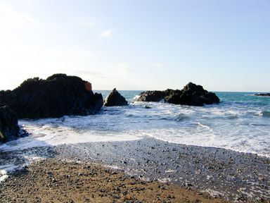 A rocky shoreline with waves washing onto a pebbled beach at Sgubor in Valley