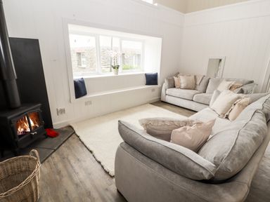 A living room with two sofas a fireplace and a window seat with cushions at Sgubor in Valley