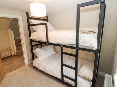 A bedroom with a black metal bunk bed with white bedding and folded towels at Sgubor in Valley