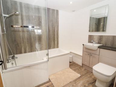 A bathroom with a bathtub shower combo sink toilet and mirror at Sgubor in Valley
