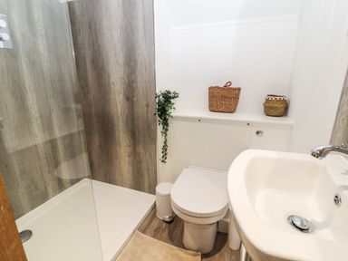A bathroom with a shower, toilet, sink, bins, and two wicker baskets at Sgubor in Valley