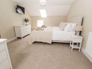 A bedroom with a bed bedside table dresser and wall mounted tv at Sgubor in Valley