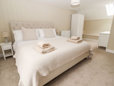 A bedroom with a large bed two bedside tables lamps a wardrobe and a chest of drawers at Sgubor in Valley