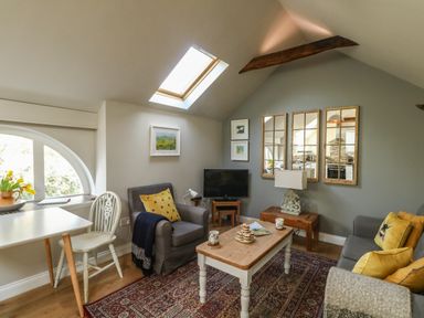 A living room with a skylight, armchairs, a coffee table, a television, and mirrors at Little Brook in Nottington near Weymouth