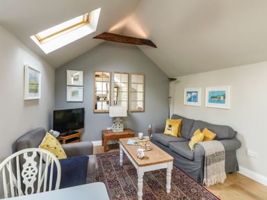 A sitting area with two gray sofas a wooden coffee table a small television and skylight at Little Brook in Nottington near Weymouth