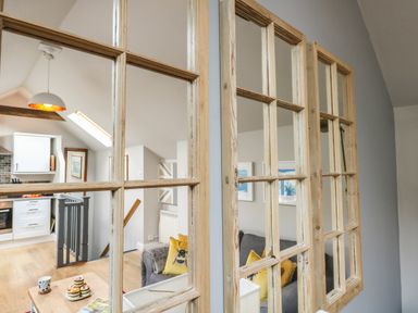 A living room and kitchen area seen through wooden window frames at Little Brook in Nottington near Weymouth