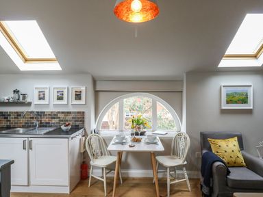 A kitchen and dining area with a small table and two chairs by a window at Little Brook in Nottington near Weymouth