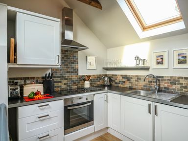 A kitchen with white cabinets black countertop and tiled backsplash at Little Brook in Nottington near Weymouth