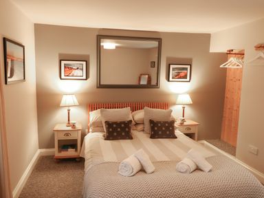 A bedroom with a double bed lamps on bedside tables framed pictures and a mirror at Little Brook in Nottington near Weymouth
