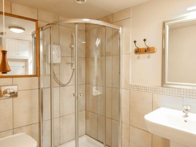 A bathroom with a corner shower with glass doors a sink and a mirror at Little Brook in Nottington near Weymouth