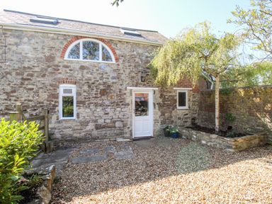 Exterior view of a stone cottage with gravel courtyard and small tree at Little Brook Nottington near Weymouth