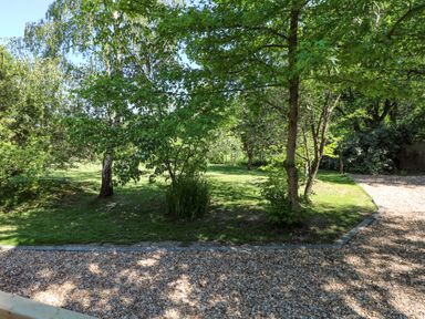 A garden area with grass and trees beside a gravel path at Orchard Lodge in Bolney