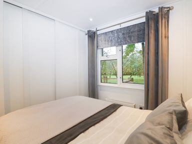 A bedroom with a bed and window at Orchard Lodge in Bolney