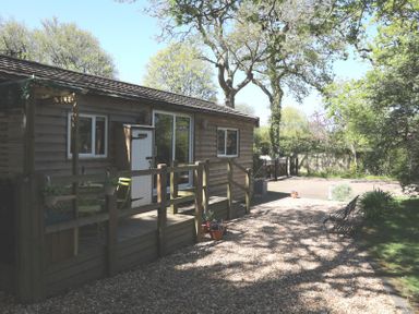A wooden cabin with a deck and trees at Orchard Lodge in Bolney